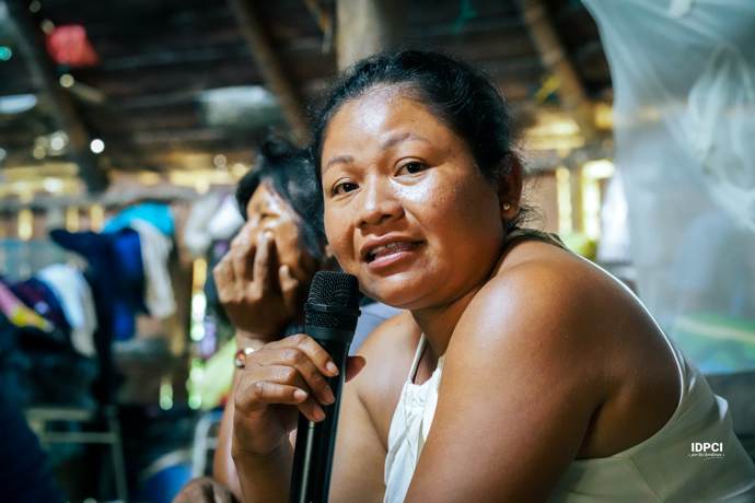 Mujer indígena interviene con micrófono en una asamblea
