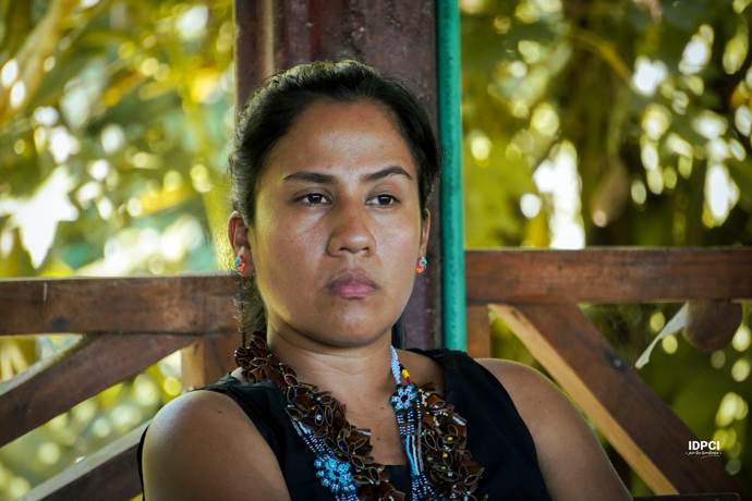 Joven lideresa con collares tradicionales en una asamblea