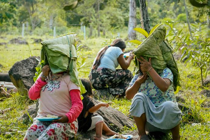 Mujeres comparten alimentos protegiéndose con hojas en el territorio